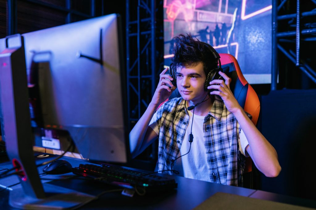 Gambar menunjukkan seorang lelaki menggunakan headphone ketika gaming.
